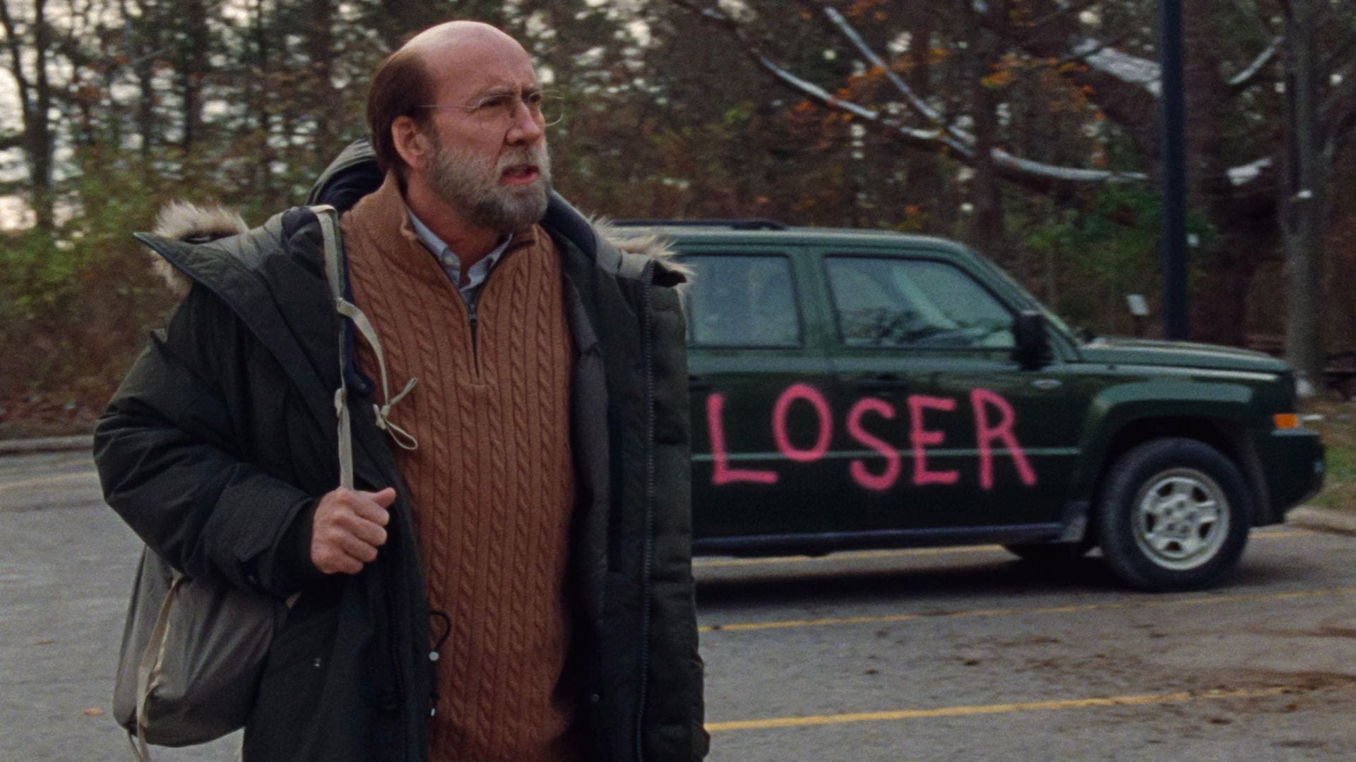 Nicolas Cage stands next to a car that has "LOSER" painted on it