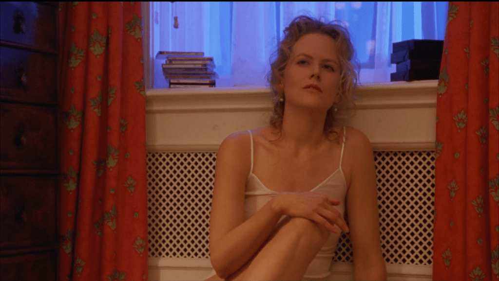 Nicole Kidman sits on the floor with a window behind her