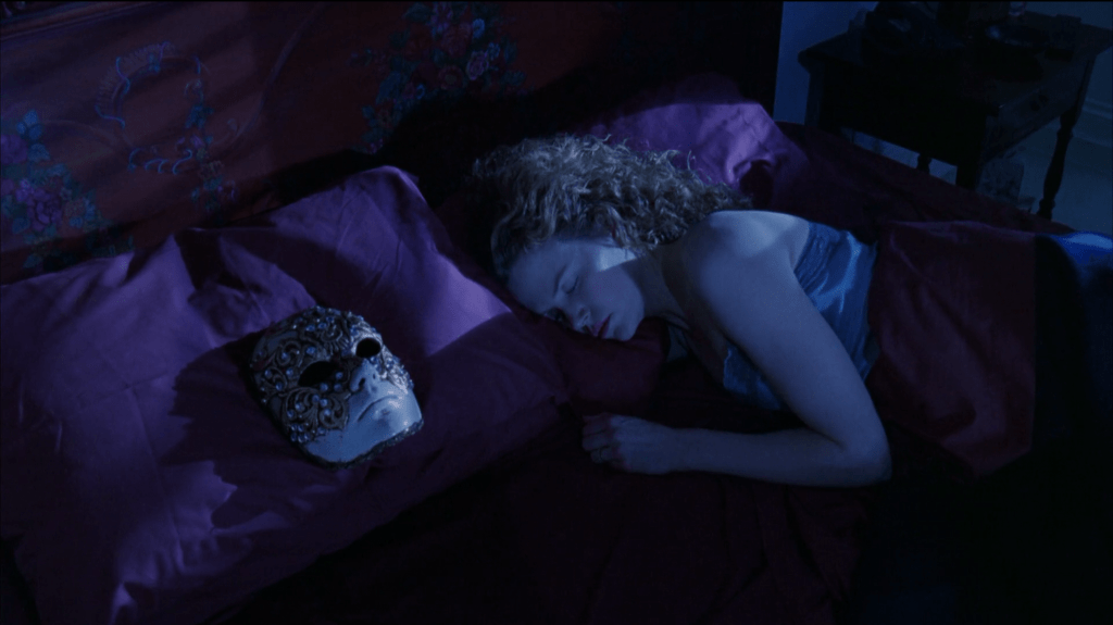 Nicole Kidman sleeps in a bed with a mask on the pillow next to her