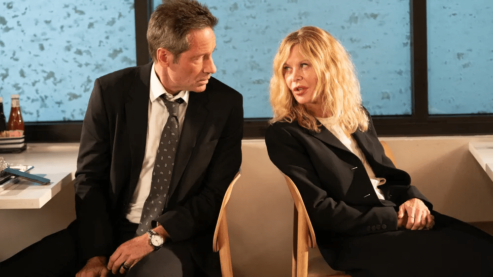 David Duchovny and Meg Ryan sit back to back as snow falls outside giant windows