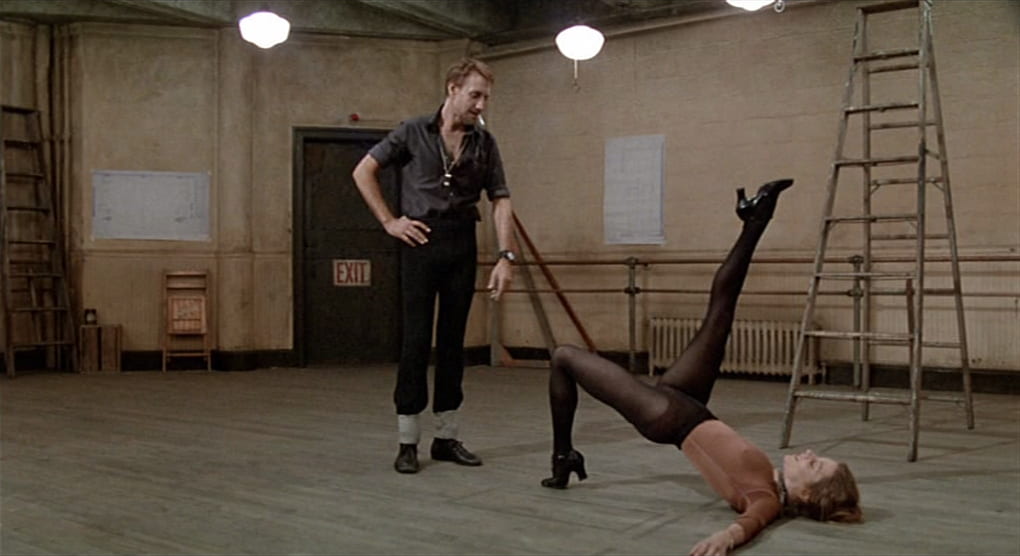 Joe watches as a woman dancer executes a move in a rehearsal studio