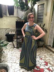 Dodez in a green and navy African dress standing in a courtyard