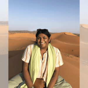 Patel in front of sand dunes with a light blue sky.