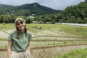 HLS Student Grace Gott stands in front of a rice field in Thailand during her semester abroad interning with the U.S. Department of State.