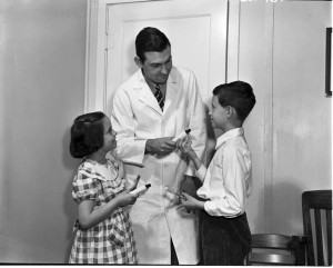 Joseph C. Muhler, DDS, PhD, of the School of Dentistry presents toothpaste and tooth brushes to two of the 12,000 young volunteers who took part in tests of a stannous flouride toothpaste. The dentifrice became the first to be recognized by the American Dental Association as ‘an effective decay-preventive agent. 