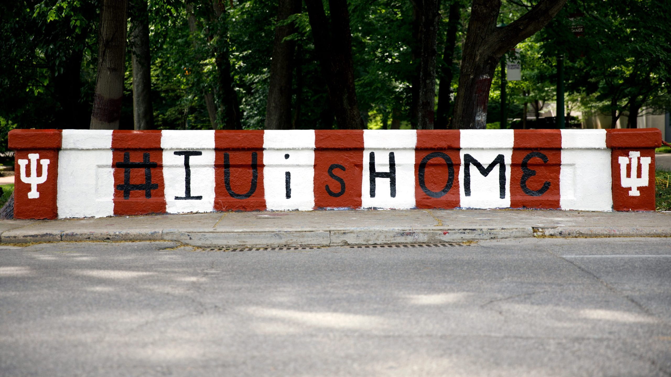 A bridge painted in cream and crimson with the text #IUisHOME painted in black letters, framed by white tridents