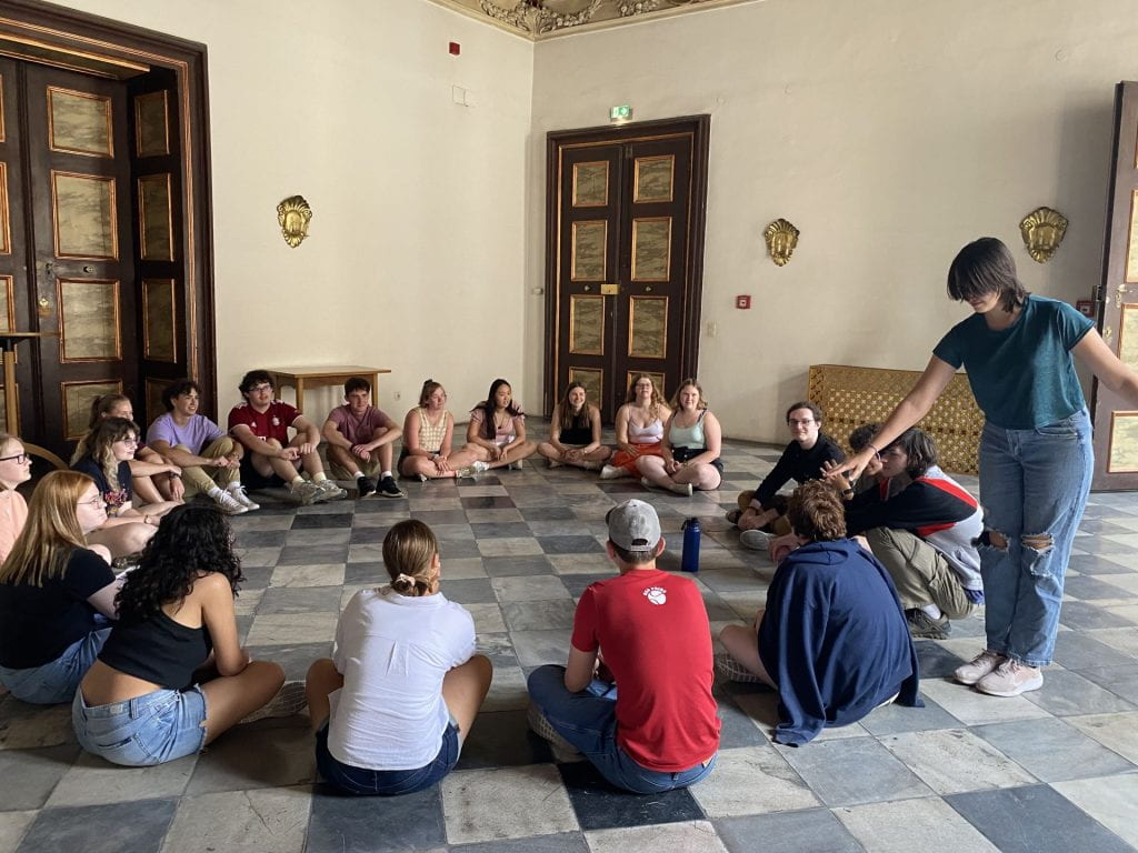 A group of students sitting in a circle, playing duck-duck-goose