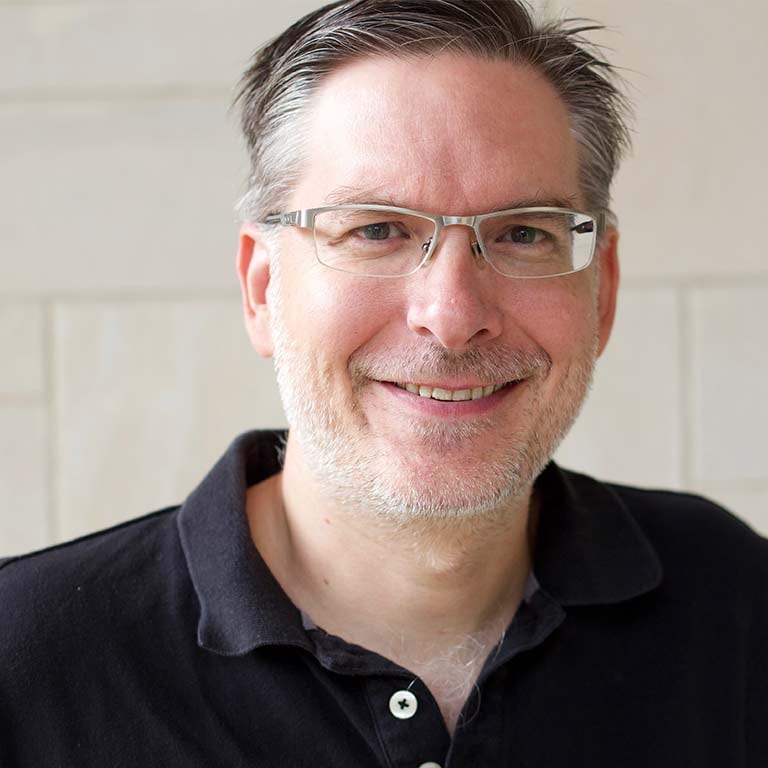 Kurt Hugenberg: A man wearing silver glasses and a blue polo shirt.