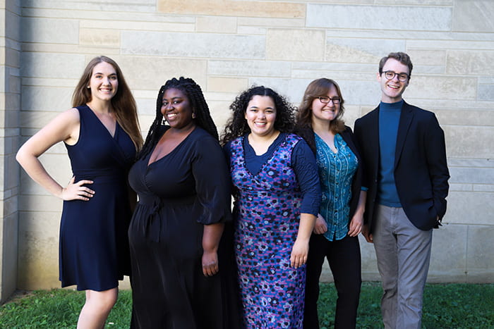 The OECD Student Leadership Team dressed in shades of blue in front of a stone wall. From left to right: Faith Kopecky, Maisah Outlaw, Ella Torres, Jamey Guzman, and Kearsen Erwin.