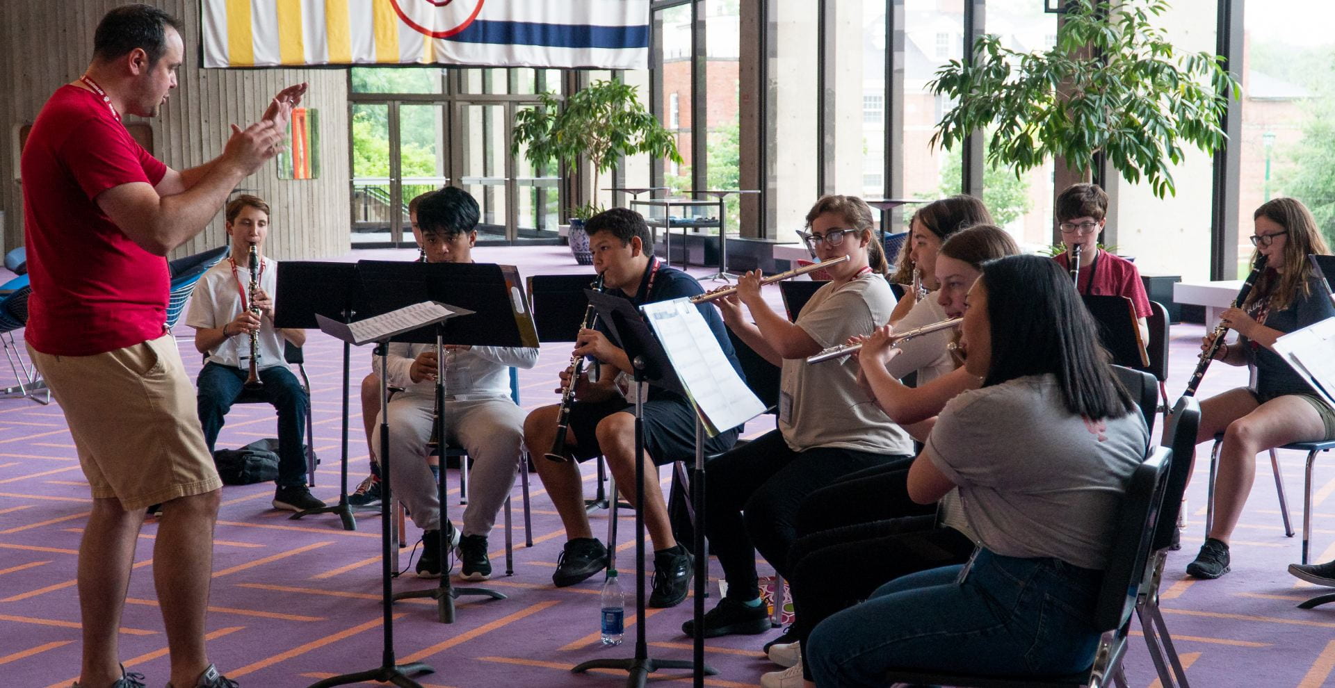 teacher conducts group of nine woodwind players in lobby