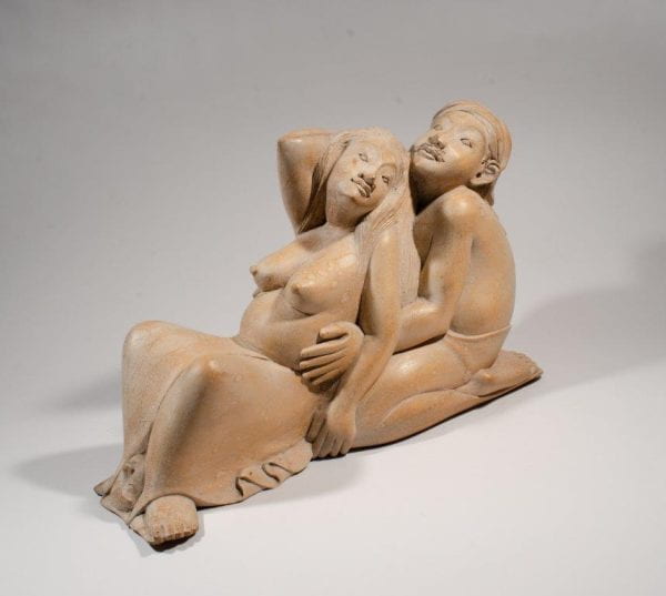 Stone sculpture of two figures semi-reclining. Topless female figure has legs spread with male figure kneeling behind supporting her with his hands. Possible depiction of labor and childbirth.