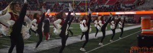 dance team kicking high during a halftime show on field