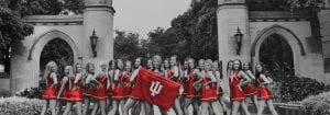dance team in red uniforms with IU flag, outside at Sample Gates