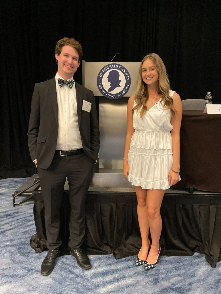 A photo of Nick Clifford and Claudia Eder in front of the Federalist Society logo