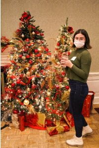 Young woman poses next to a decorated christmas tree