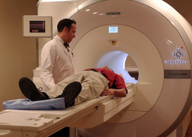 A doctor inserts a patient into a large cylindrical MRI scanner.
