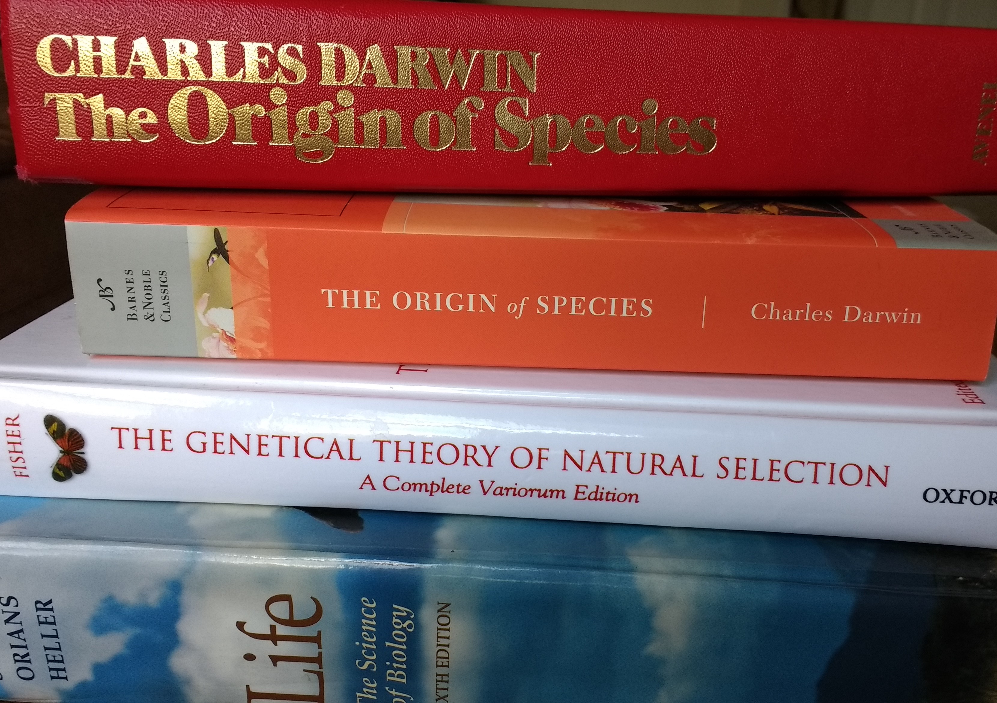 a stack of biology books, including On the Origin of Species