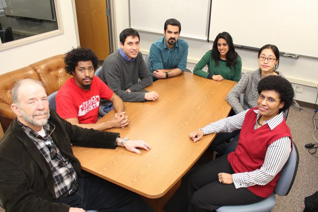 A group photograph of seven members of the Mathematical Psychology Lab, sitting around a conference table.
