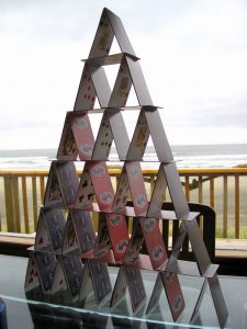 Pairs of cards leaning against each other form triangles that stack on top of other pairs to form a pyramid of cards with six layers.