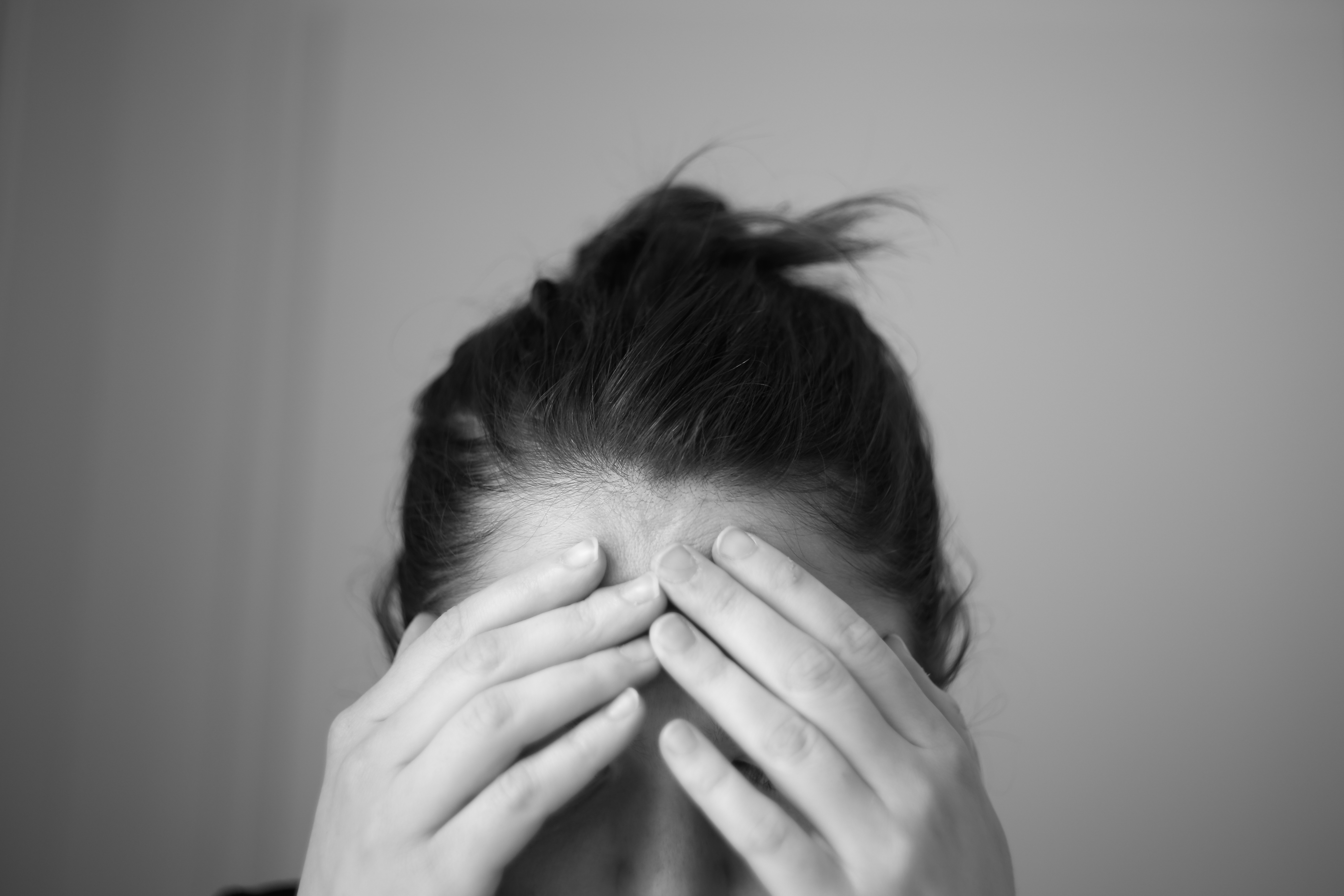 A black and white photo of a woman covering her face with her hands