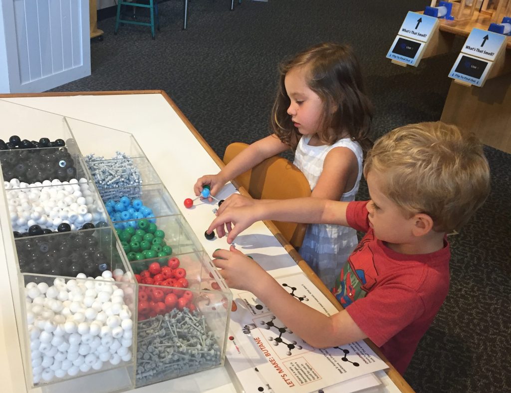 children sitting at a table playing with molecular models