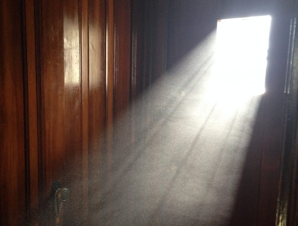 An image of a light beam from window that illuminates the dust in the air, forming a clear white beam in a darkened room.