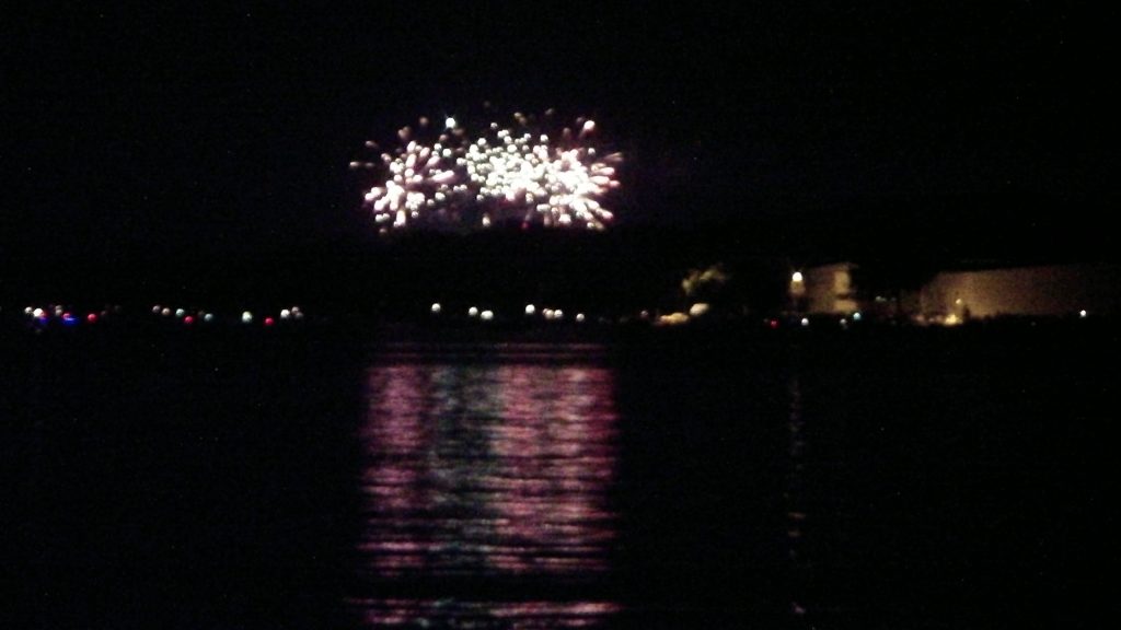 A blurred image of fireworks exploding at night over a lake.