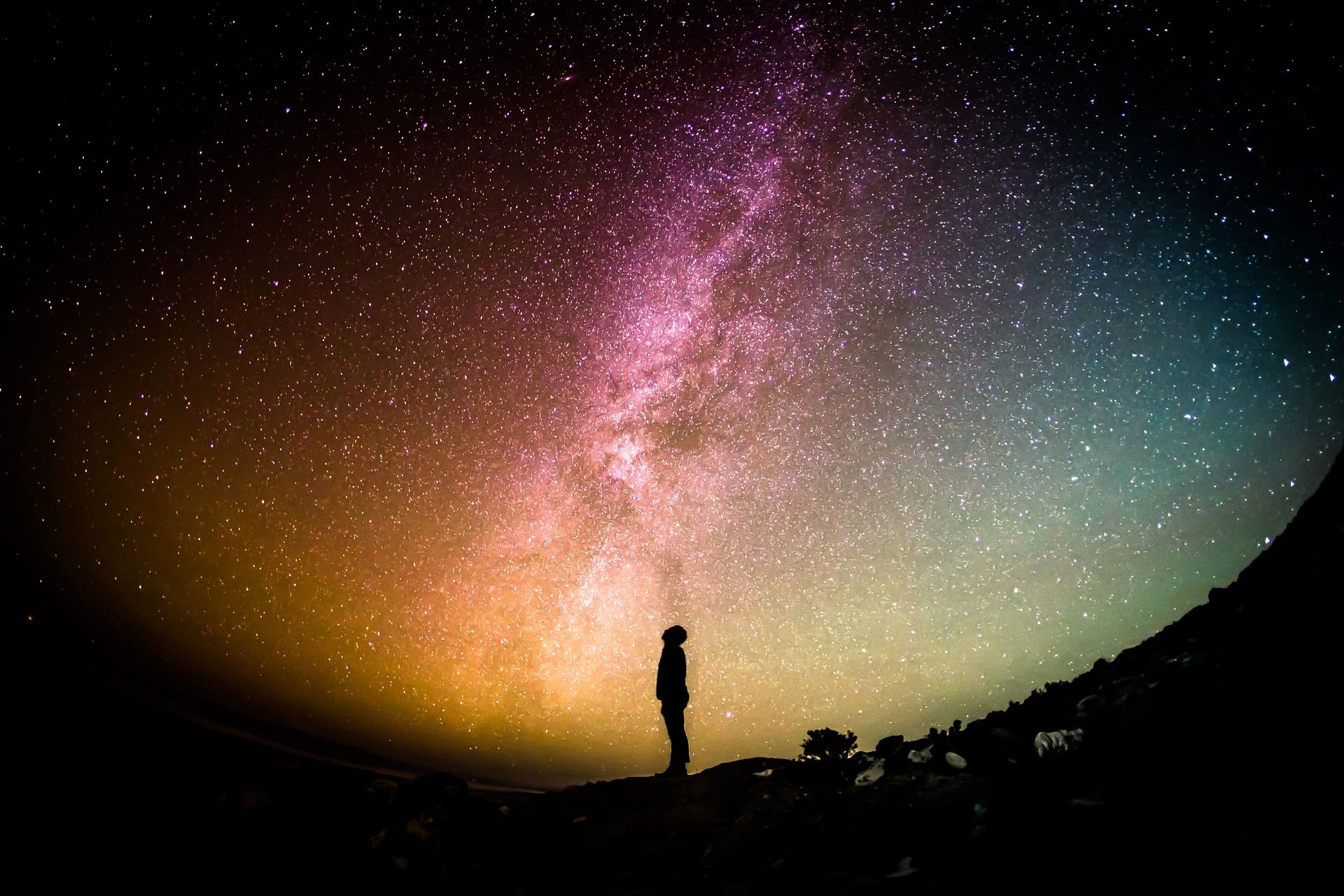 A man stands and looks up into a very starry sky.