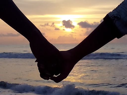 A couple holding hands during a sunset.