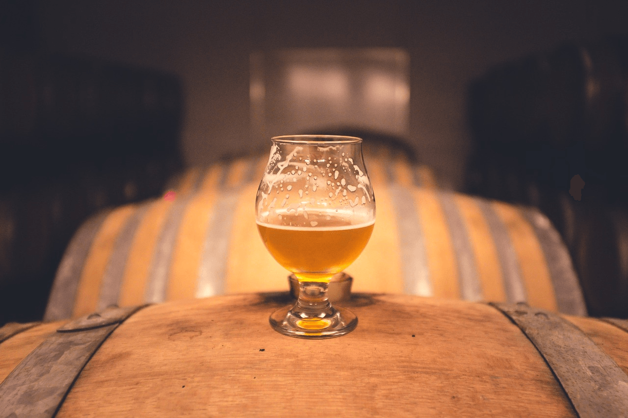 A beer glass sits on a barrel.