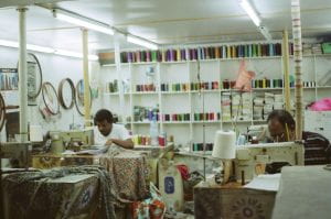 Two people working in a sweat shop sewing clothes.