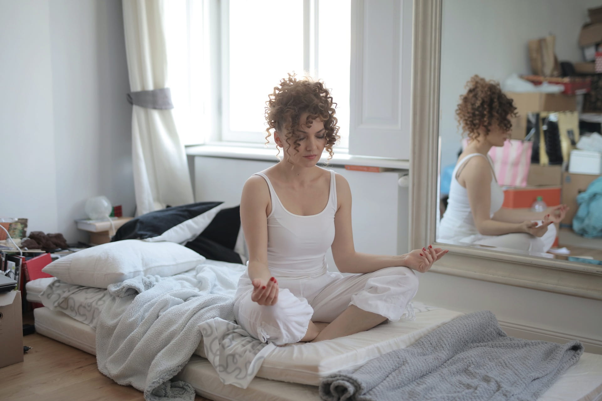 [calm-woman-in-lotus-pose-meditating-after-awakening-at-home]