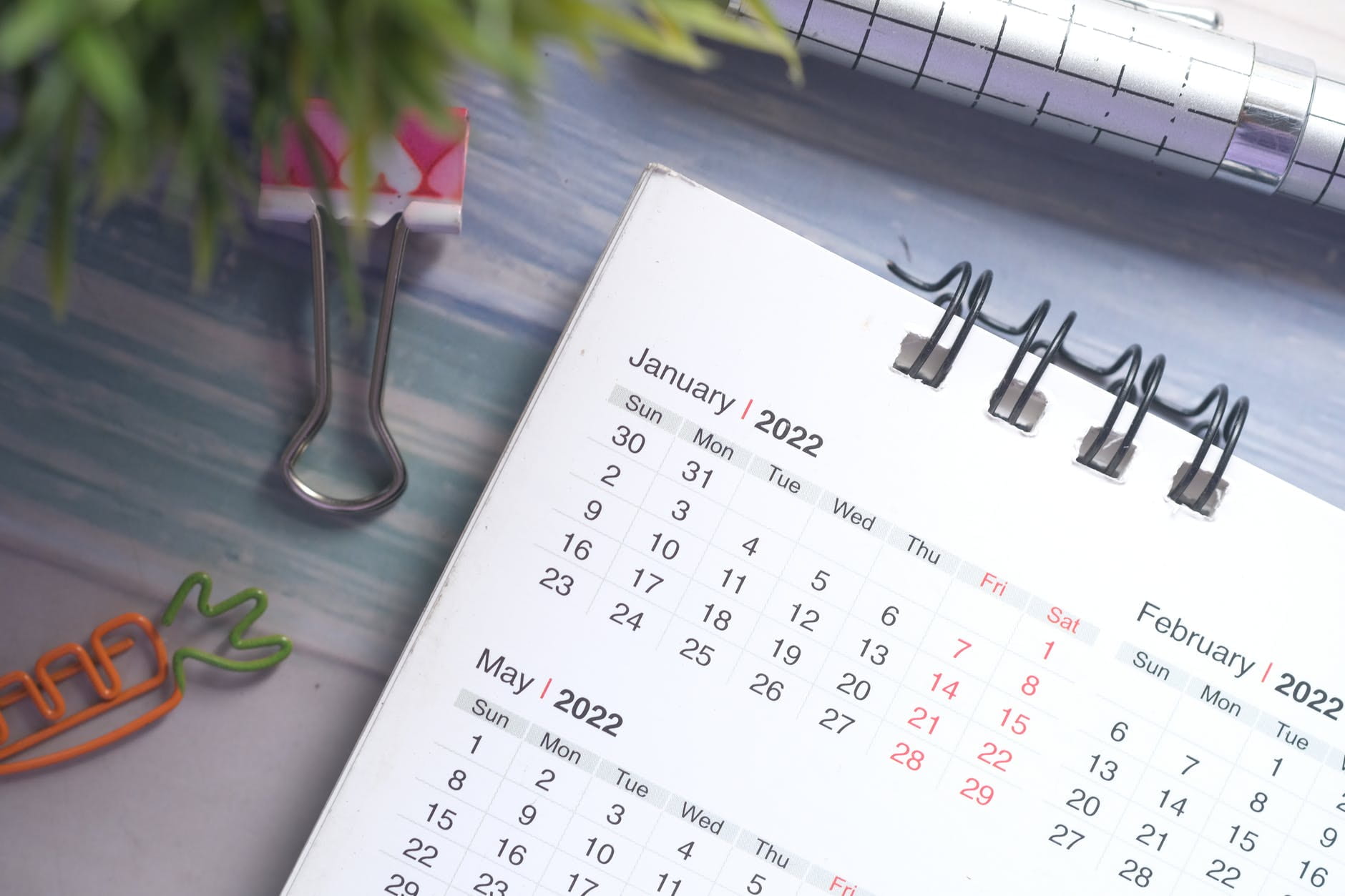 The top left corner of a spiral calendar is shown, displaying January 2022 and parts of February and May 2022. Several clips are around the notebook. 