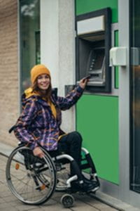 Woman in a wheelchair operating an ATM machine.