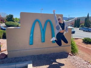 Girl jumping in front of McDonald's Green Sign in Sedona, Arizona